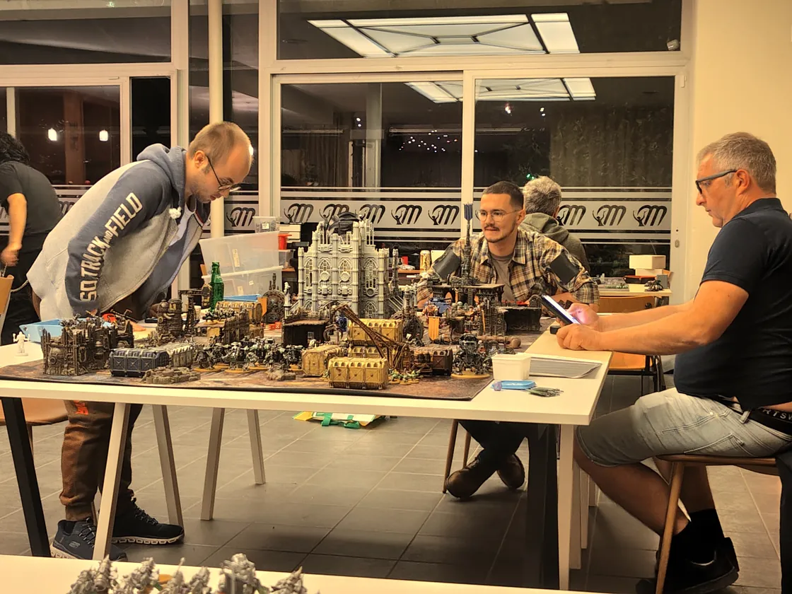Tabletopspelers rond een tafel met miniaturen en terrein